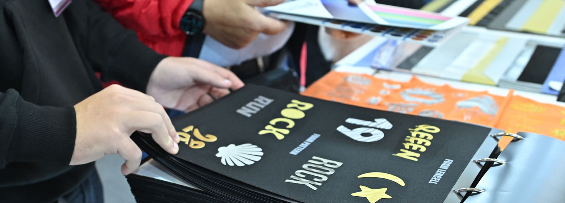 Attendees browsing a catalogue featuring creative print and design samples at a trade fair