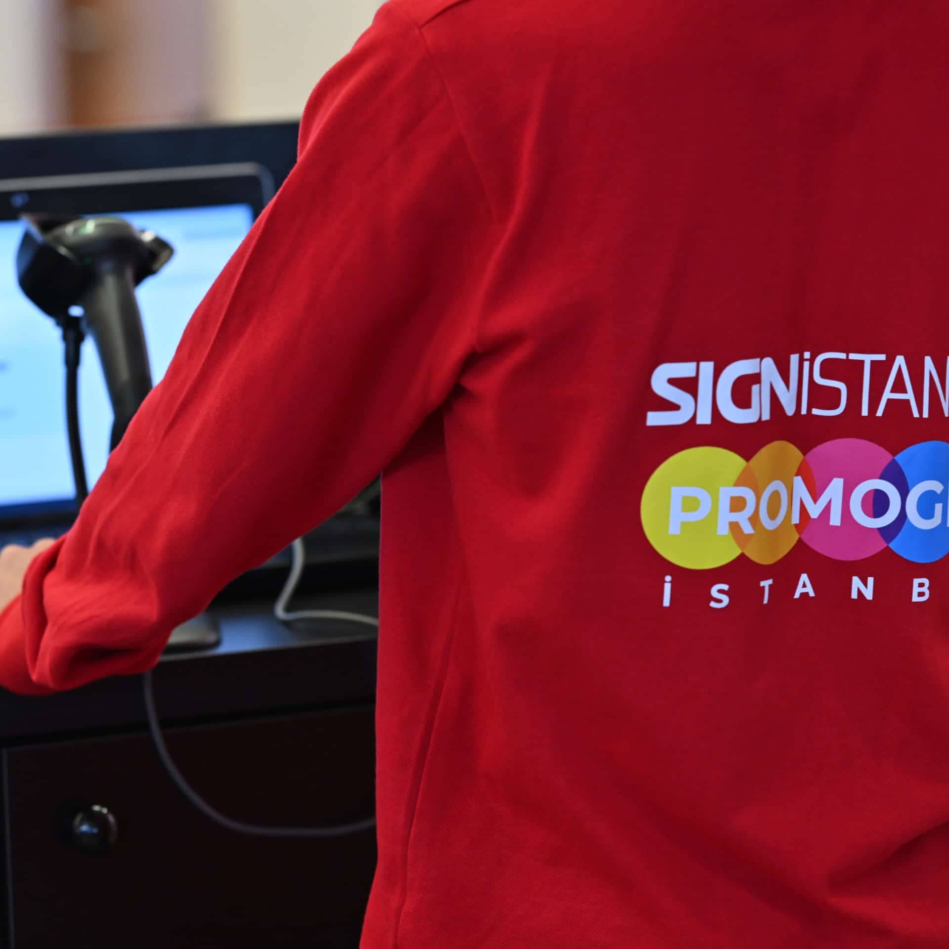 Event staff wearing a red uniform assisting at the trade show registration area with a barcode scanner