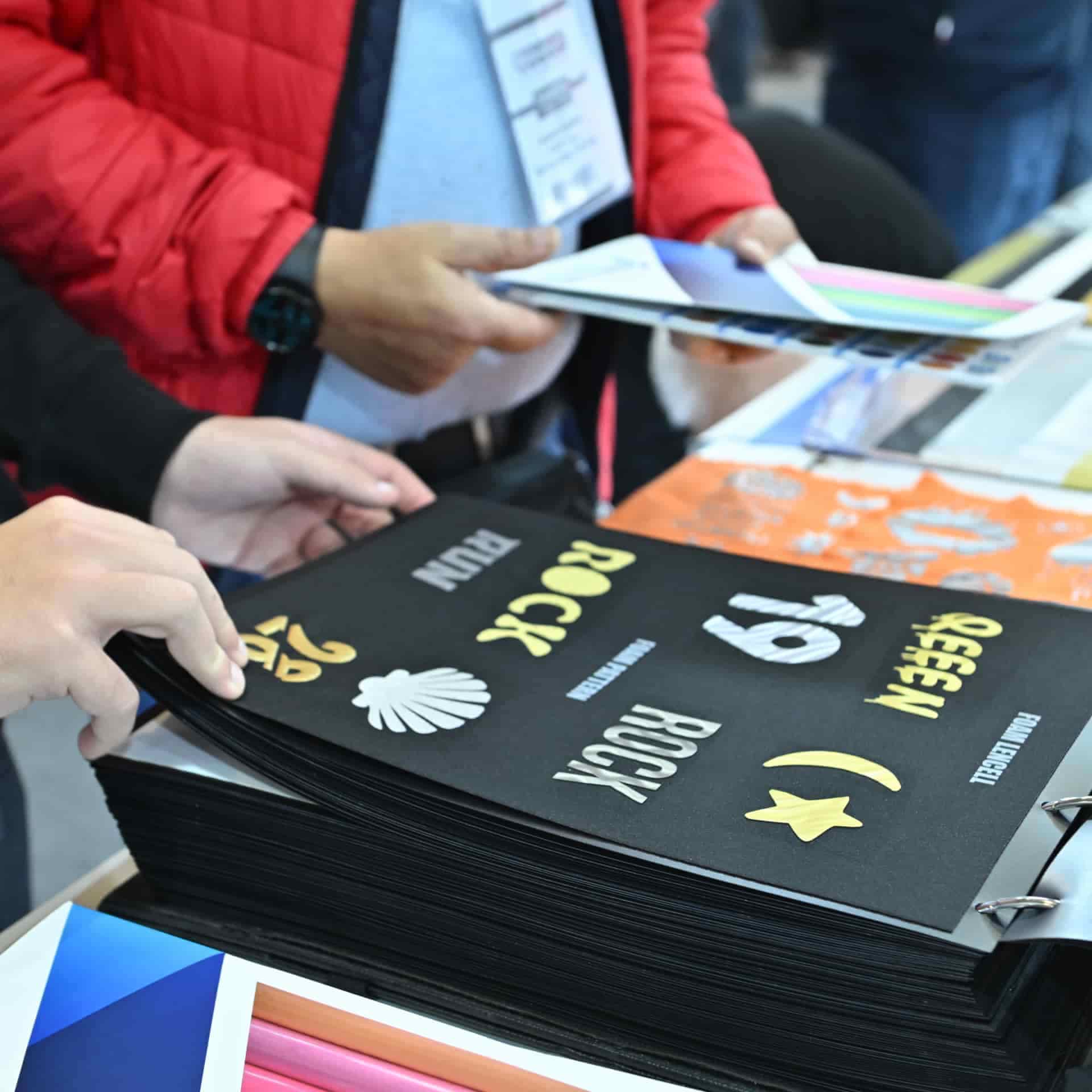 SIGN İstanbul fuar kataloğunu inceleyen bir ziyaretçi, baskı ve markalama örnekleri içeriyor