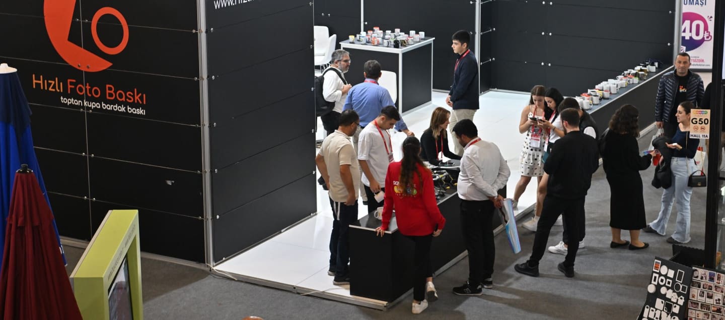 Visitors networking and discussing in the exhibition hall at SIGN İstanbul, with product displays in the background