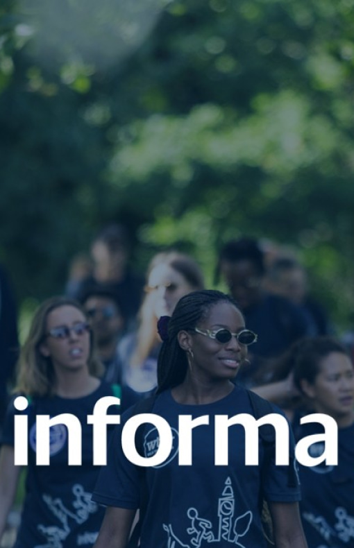 Informa Markets markalı tişörtler giymiş bir grup insan, şirket logosu olan yeşil park arka planıyla dışarıda yürüyor.
