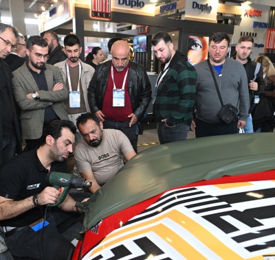 Crowd watching a live car wrapping demonstration showcasing vinyl application techniques at SIGN İstanbul