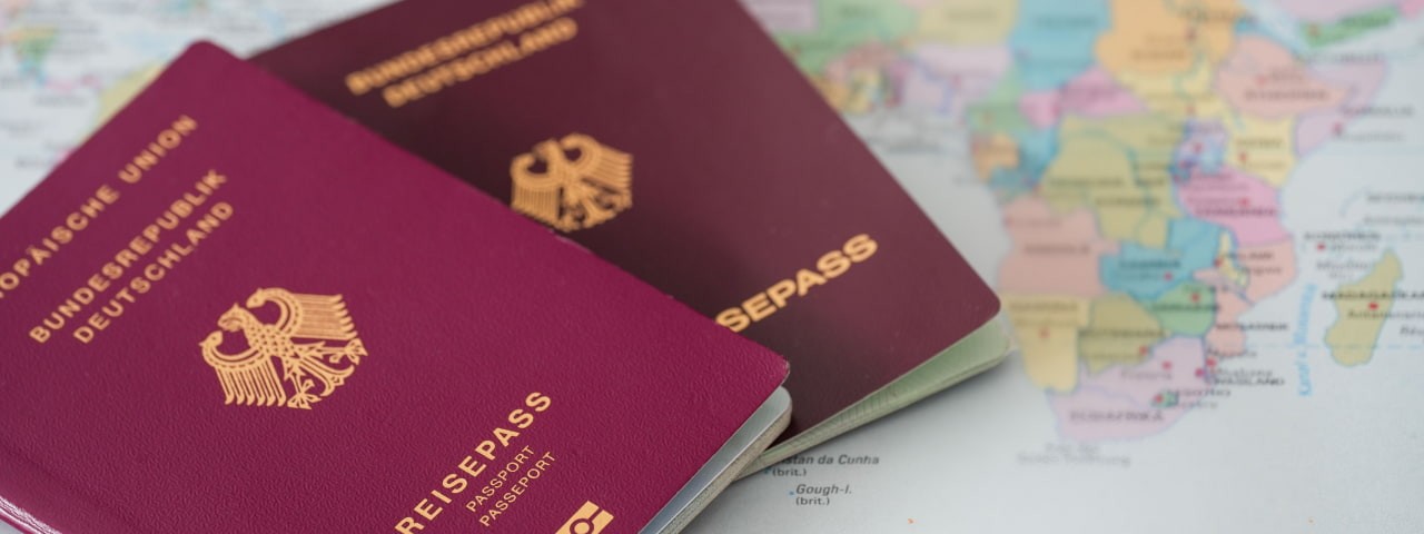 Closeup of a hand holding a passport at an airport with an airplane and luggage in the background
