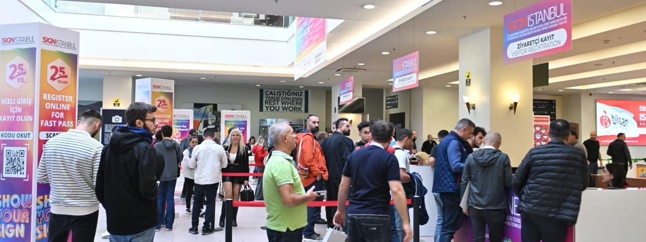 Visitors lining up for registration at SIGN İstanbul, with colorful banners and signs in the venue