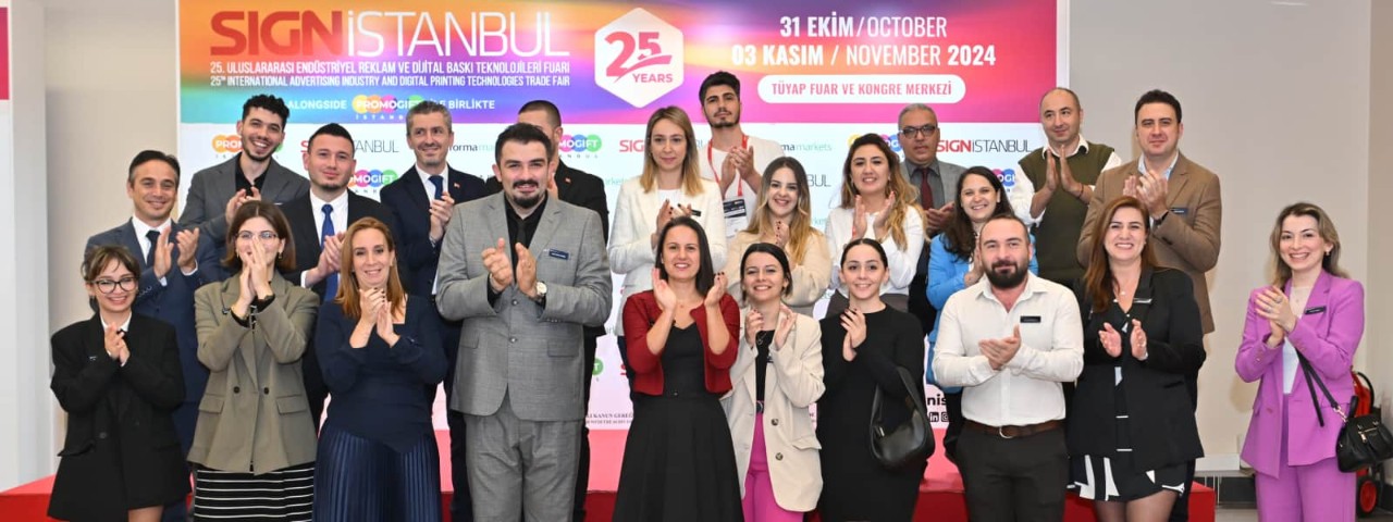 SIGN İstanbul ekibinin, etkinlik tabelası önünde alkışlarken çekilmiş grup fotoğrafı.