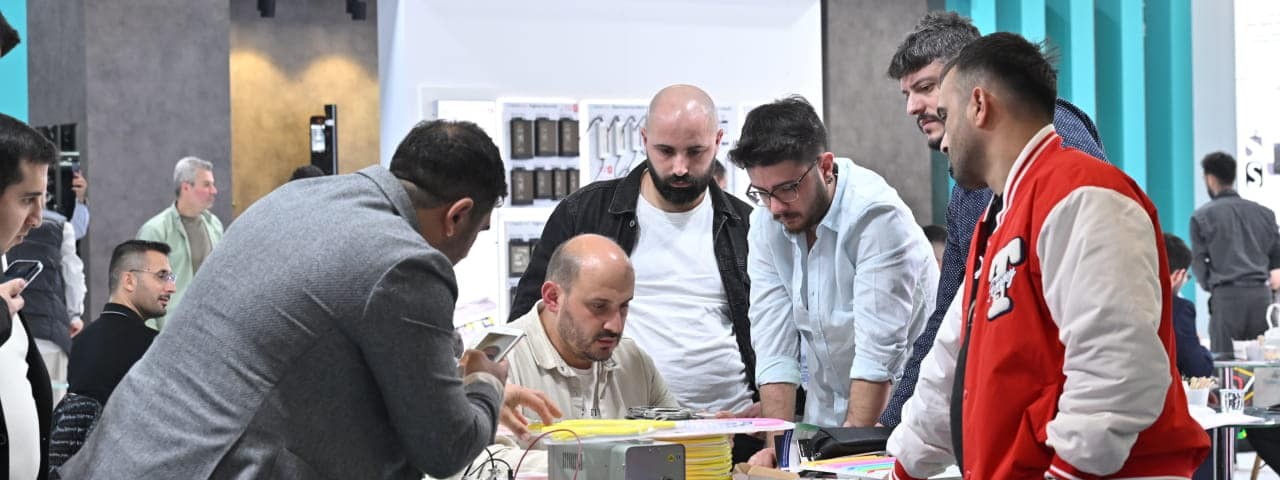 SIGN İstanbul standında sergilenen bir ürünü inceleyip tartışan katılımcılar grubu.